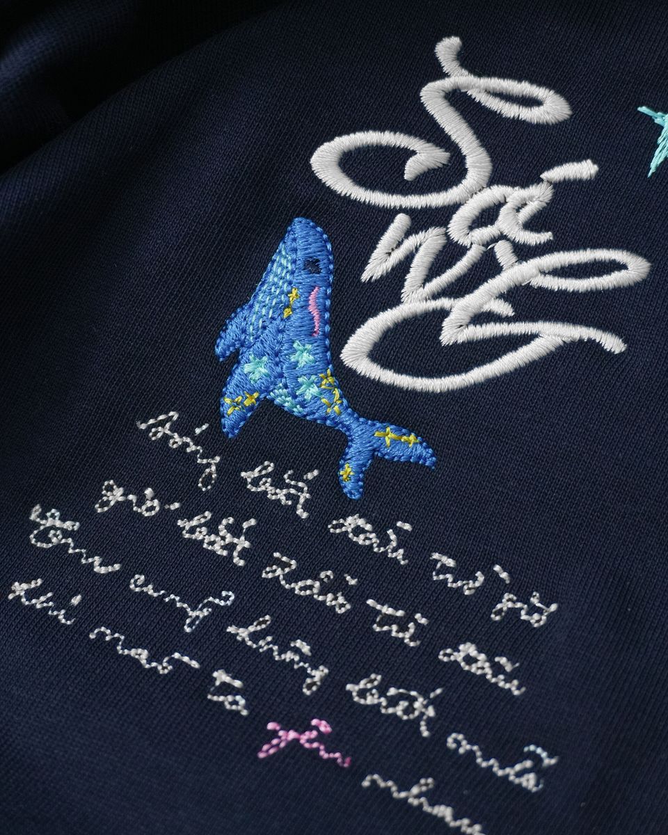 Dấu Sóng thêu chỉ trắng cùng cá voi xanh trên ngực áo thun Sóng